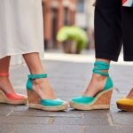 Stylowe kobiece koturny na tle miejskiej ulicy z fakturowaną nawierzchnią, naturalne światło, wyraźne detale.